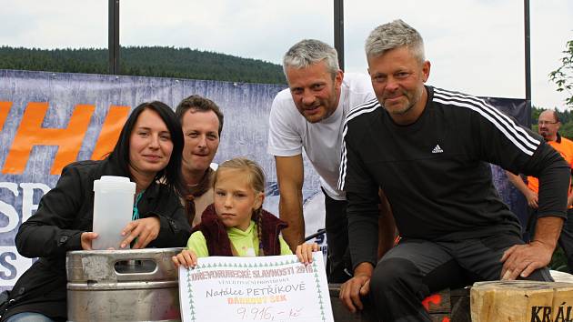 ŠEK. Na Dřevorubeckých slavnostech převzala Natálka Petříková šek s částkou 9 916 korun. Díky daru po jeho předání se celkový výtěžek ještě o jednu tisícikorunu zvýšil. Na snímku jsou nad Natálkou zleva maminka Jana, Petr Aksamit a Luboš a Petr Šulistovi.