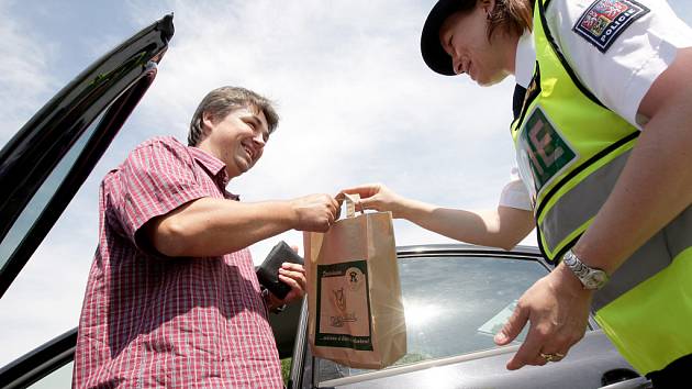 Policistka předává slušnému řidiči pivo.