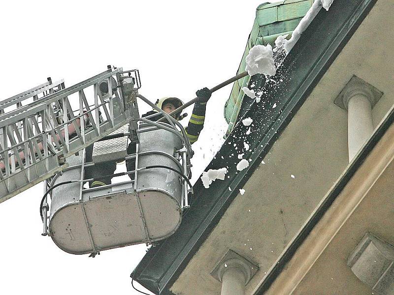 Brněnští hasiči sundávají sníh ze střech domů.