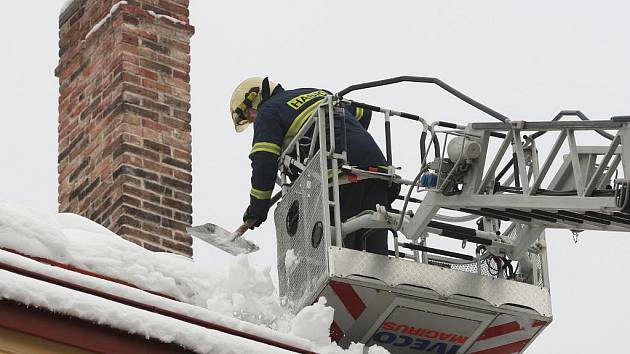 Hasiče zaměstávají převisy mokrého a těžkého sněhu na střechách domů.