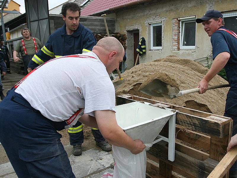 Hasiči ucpávají pytli s pískem umělou hráz říčky Litavy u Měnína na Brněnsku.