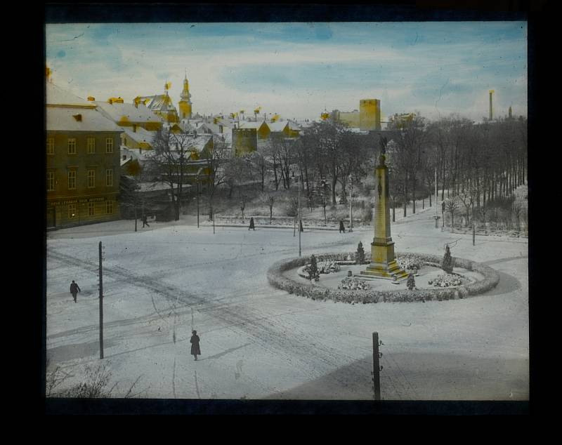 Celkový pohled na Komenského náměstí ve Znojmě s Kopalovým pomníkem a Husovými sady v pozadí v zimě. Zachycena i budova Nové lékárny (1918-1938).