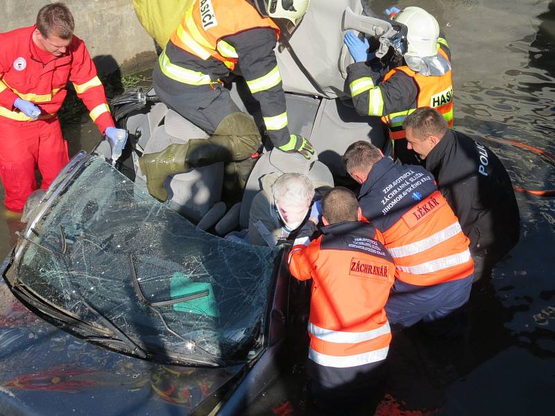 Auto převrácené na střechu potopené střechou do bahna. Řidič v něm zůstal připoutaný k sedadlu. A zraněný.