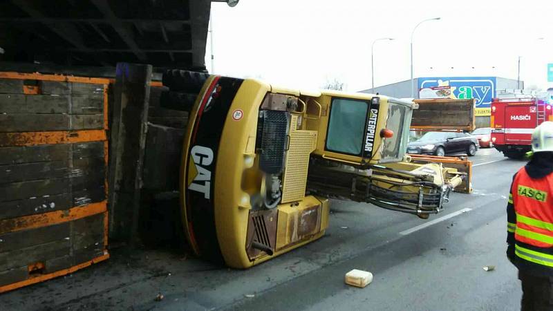 Nehoda nákladního auta převážejícího bagr v brněnské Hněvkovského ulici.