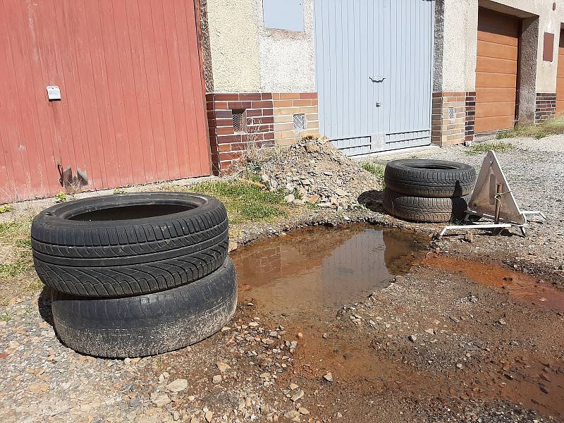 Majitelé marně bojují proti vodě vytékající před garáže.