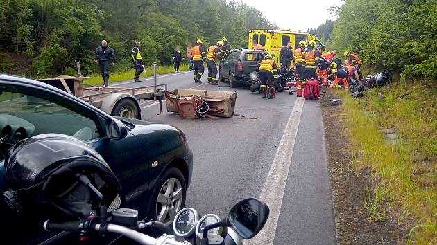 Z nehody tří motorek a osobního vozu s přívěsným vozíkem.