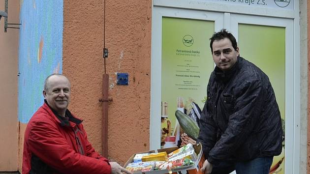 Ředitel potravinové banky Milan Hloušek (vpravo) vydává ze skladu potraviny Liboru Račkovi, vedoucímu Pečovatelské služby v Kynšperku nad Ohří