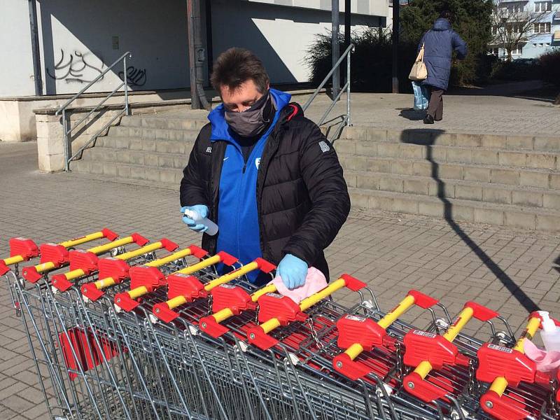 Členové realizačního týmu FC MAS Táborsko pomáhají dezinfikovat košíky a roznášet seniorům nákupy.