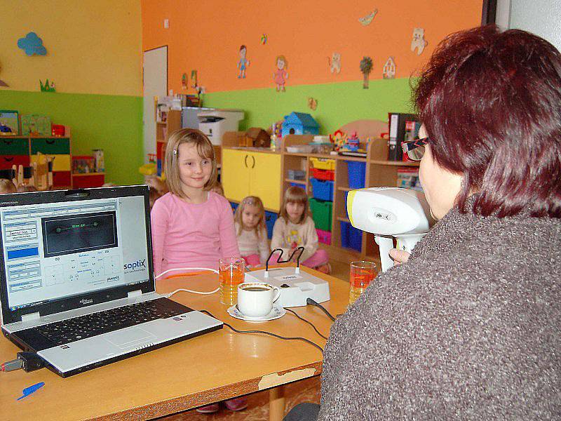 VYŠETŘENÍ ZRAKU. Zdravotní sestra vyšetřuje zrak takzvaným videoretinoskopem, který umí na místě zjistit oční vady u vyšetřovaných osob. 