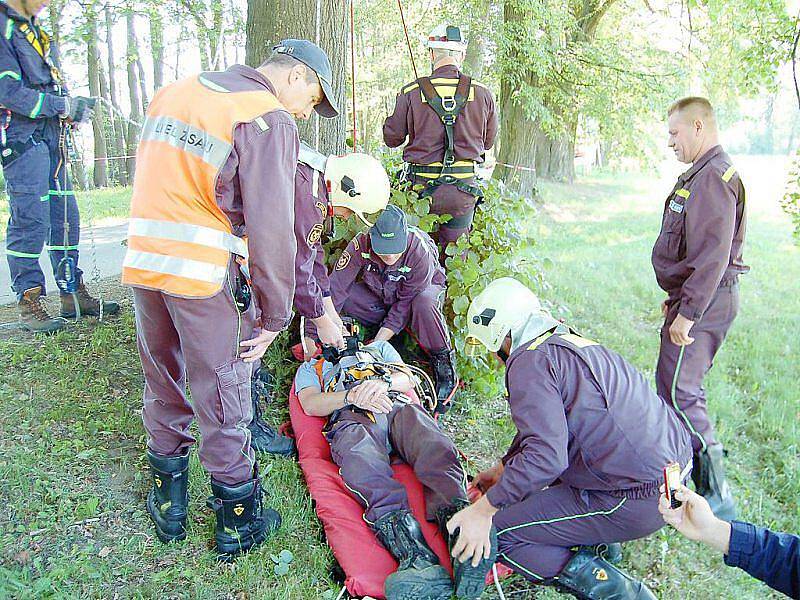 VYPROŠTĚN. Hasiči v rámci taktického cvičení zachraňují figuranta v roli parašutisty, který přistál na stromě.