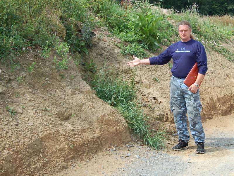 Martin Pohl ukazuje na místo, kde byl dříve vjezd na jeho pole. Nyní tam je navezen několik metrů vysoký val, který tam vznikl v rámci  výstavby nové úvozové cesty. 