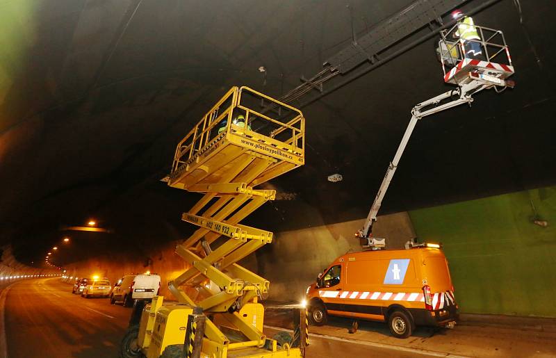 Dělníci opravují v tunelu dálnice D8 Panenská část elektroinstalace a čistí signalizační prvky od nánosu sazí.