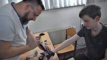 Vedoucí ústeckého CoderDojo Jiří Vilímek instaluje Daliborovi Andree prototyp rukavice pro nevidomé.