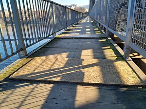 Lávka pod železničním mostem v Ústí nad Labem. Část je opravená, část ovšem stále trpí četnými dírami, které město nechalo překrýt dřevotřískovými deskami.