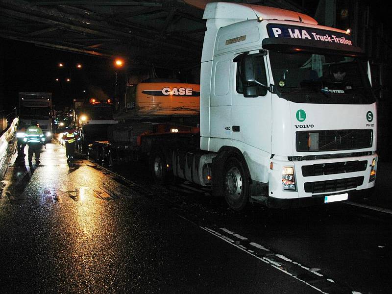 Řidič tahače přepravující bagr na návěsu, podcenil podjezdovou výšku železničního mostu ve Střelecké ulici a stavební stroj doslova napasoval pod most. 