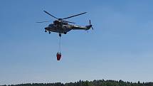 Oheň hasí vojenská helikoptéra a dvě letadla. Vodu jim doplňují uprostřed nesnesitelného vedra dobrovolní hasiči, například telnická jednotka, ve které dobrovolně slouží i zdejší starosta Jan Doubrava.