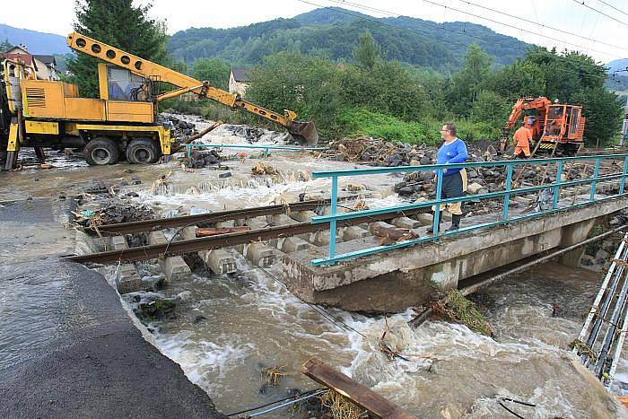 Obec Těchlovice: Obrovské kameny, písek a hlínu nyní odklízí těžká technika, ale stále přitékající voda komplikuje čištění tratě.