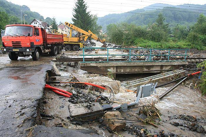 Obec Těchlovice: Obrovské kameny, písek a hlínu nyní odklízí těžká technika, ale stále přitékající voda komplikuje čištění tratě.