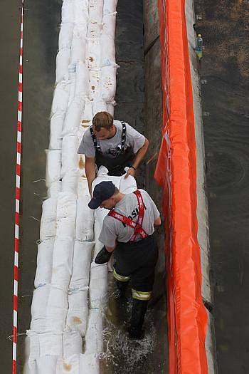 Voda zatopila Přístavní ulici v Ústí nad Labem. Na místě zasahují profesionální i dobrovolní hasiči, kteří pytlují vaky, kterými se snaží utěsnit komunikaci. Vodu z ní poté odčerpají.