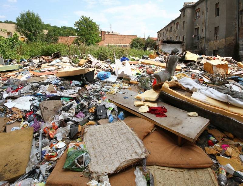 Vnitroblok domů ve Sklářské ulici je plný odpadků. Mezi nimi si hrají děti. 