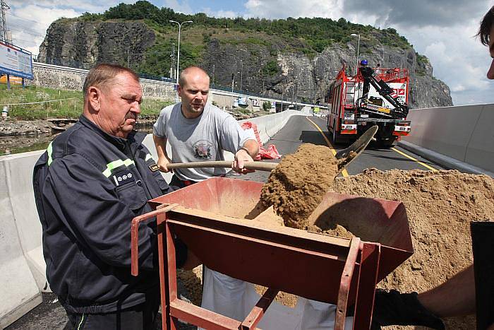 Voda zatopila Přístavní ulici v Ústí nad Labem. Na místě zasahují profesionální i dobrovolní hasiči, kteří pytlují vaky, kterými se snaží utěsnit komunikaci. Vodu z ní poté odčerpají.