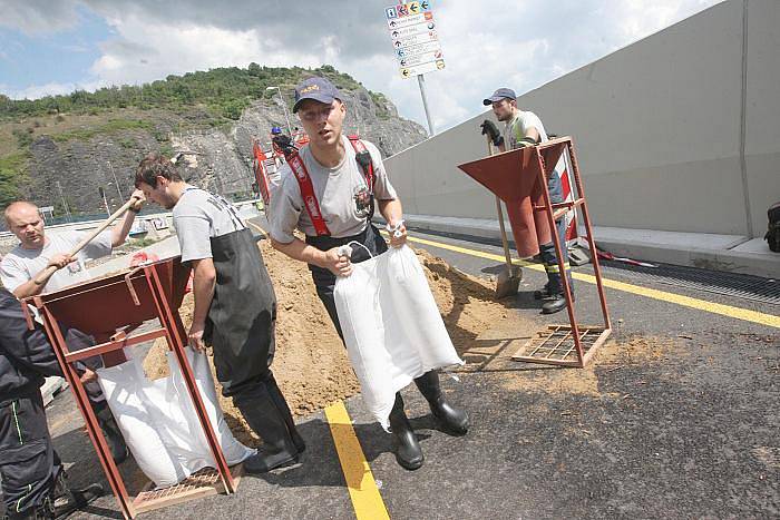 Voda zatopila Přístavní ulici v Ústí nad Labem. Na místě zasahují profesionální i dobrovolní hasiči, kteří pytlují vaky, kterými se snaží utěsnit komunikaci. Vodu z ní poté odčerpají.