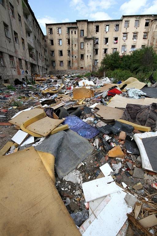 Vnitroblok domů ve Sklářské ulici je plný odpadků. Mezi nimi si hrají děti. 