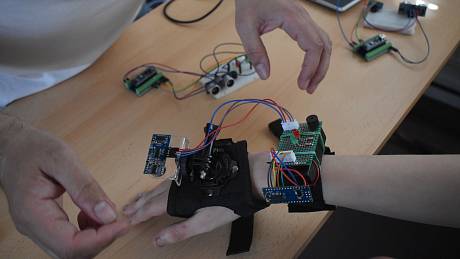Vedoucí ústeckého CoderDojo Jiří Vilímek instaluje Daliborovi Andree prototyp rukavice pro nevidomé.