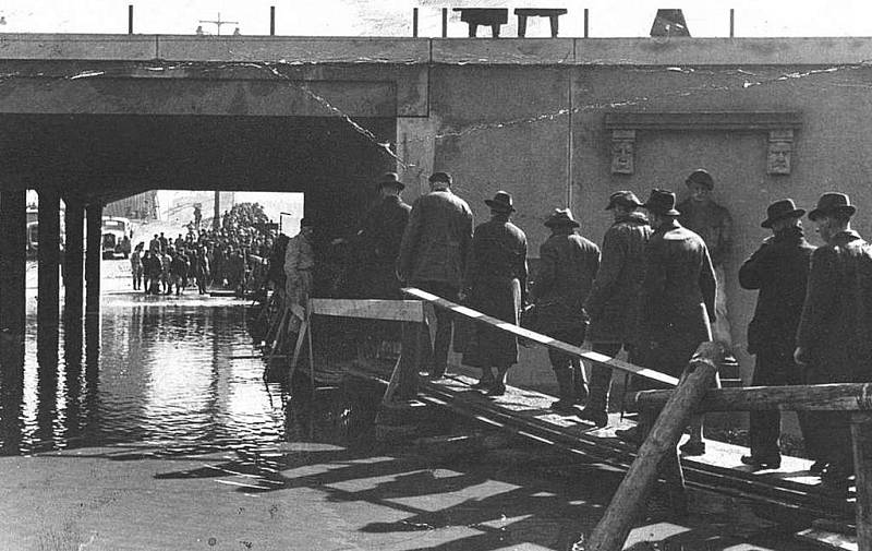 chodníček z prken do viaduktu pod tratí k mostu přes Labe. Přecházení úzkých lávek řídili tehdy příslušníci nacistické polovojenské organizace SA.