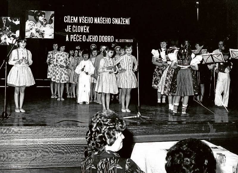 KAŠAVA, S DOBOVÝMI HESLY. Kulturní vystoupení kašavských dětí, snímek pochází z přelomu 70. a 80 let.