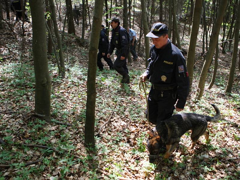 Policisté se psy prohledávají místo nálezu kostry člověka.