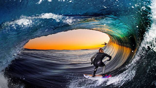 Jeden z nejúžasnějších záběrů. Gigantická vlna tvoří vodní tunel a surfaři si užívají netradiční výhled na západ Slunce.