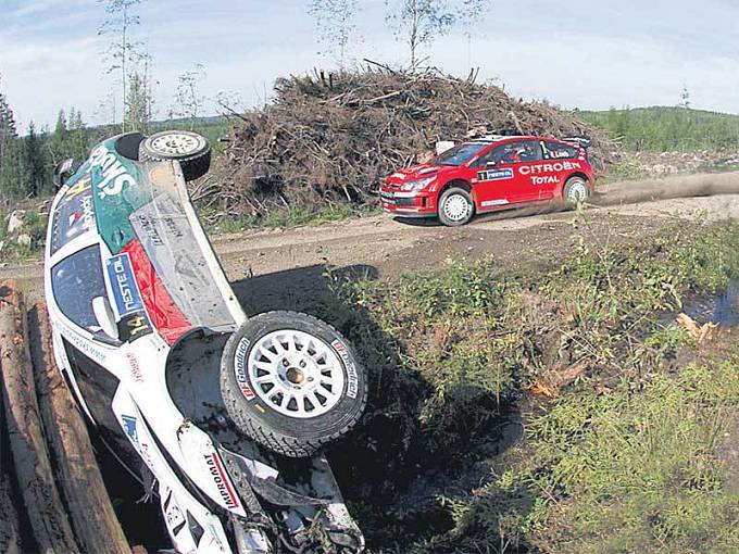 Kopeckého škodovka leží roztřískaná v příkopu, kolem ní frčí Loeb.