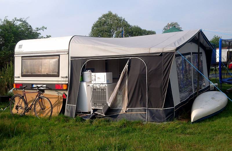 Letní byt kamarádů z Ostravy, kteří si plní svůj sen. Komfort v přístřešku u karavanu, takřka jako doma.