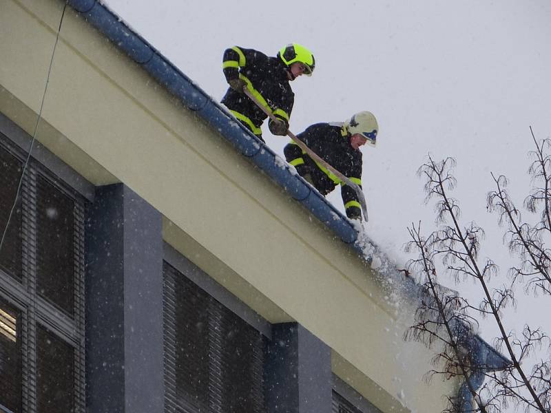 Odklízení sněhu ze střechy ZŠ Březinova v Ostravě-Hrabůvce.