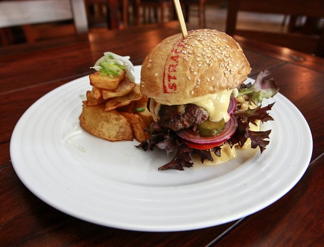 SPECIALITA PODNIKU. Letní specialitou je Stračena hovězí burger podávaný v domácí sezamové bulce s gratinovaným kravským domácím sýrem, restovanou slaninou, zastřeným vejcem, salátovými lístky, cibulkou, rajčaty a nakládanou okurkou. 