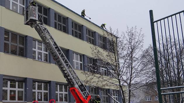 Odklízení sněhu ze střechy ZŠ Březinova v Ostravě-Hrabůvce.