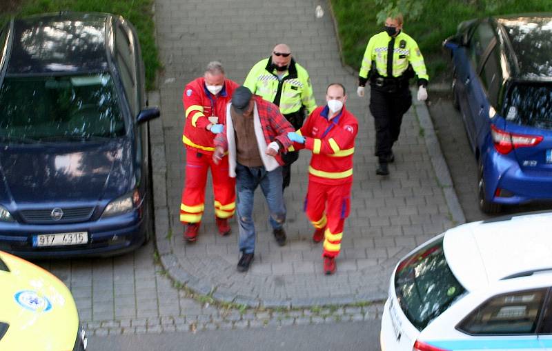 Zatím poslední, nedělní, odvoz opilého pobudy od „prokleté“ lavičky, zdravotníkům asistují strážníci.