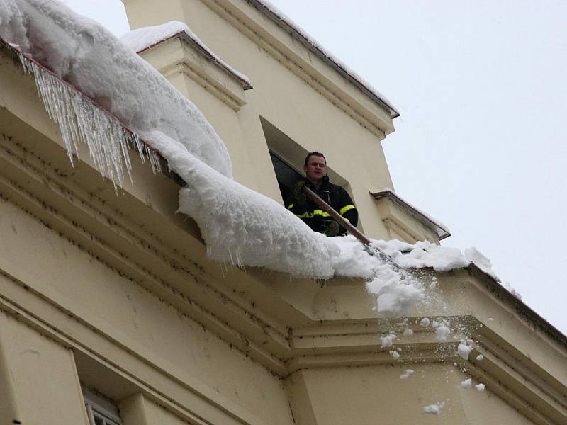 Hasiči v pondělí po poledni shazovali hromady sněhu ze střechy domu v ostravské Nádražní ulici.