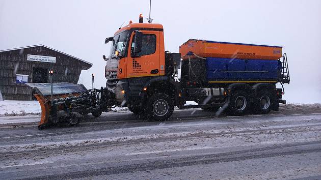 Sypače soukromé firmy Stavby, opravy a údržba silnic při zimní údržbě silnice na Červenohorském sedle.