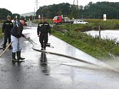Sudkovští dobrovolní hasiči čistili včera silnici od bláta, které naplavila rozbouřená Desná.