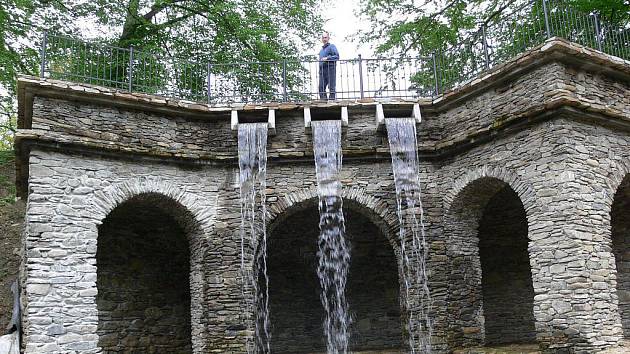 Přes oblouky umělé jeskyně v zámeckém parku v Loučné nad Desnou už stéká vodopád