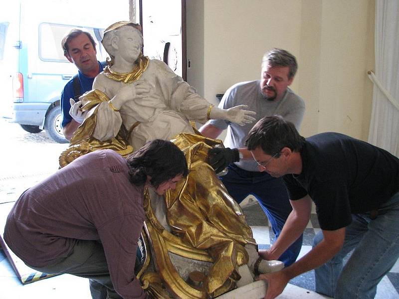 Řemeslníci vracejí sochu anděla na jeho místo v šumperském klášterním kostele