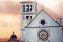 Slunce se protlouká skrze mraky nad hlavní katedrálou v Assisi.