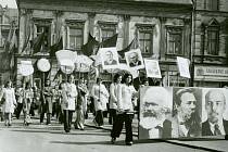 Účastníci průvodu s transparenty a podobiznami komunistických model – Marx, Engels, Lenin, v pozadí Brežněv a Husák.