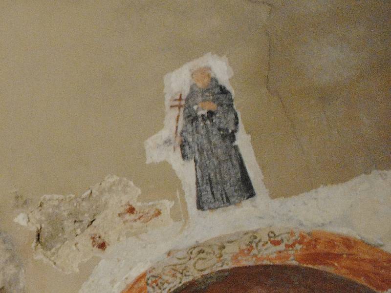 Postava františkána nad lavabem, umývadlem pro kněze, v barokní vrstvě omítky zákristie.