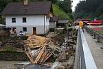 Voda s bahnem valící se v sobotu odpoledne dolů rájovským kopcem tady poškodila silnici, most i vedle stojící dům.