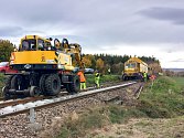 Uzavřený přejezd v Třísově. Nový kolejový rošt na trati pokládá obnovovací stroj SMD 80.