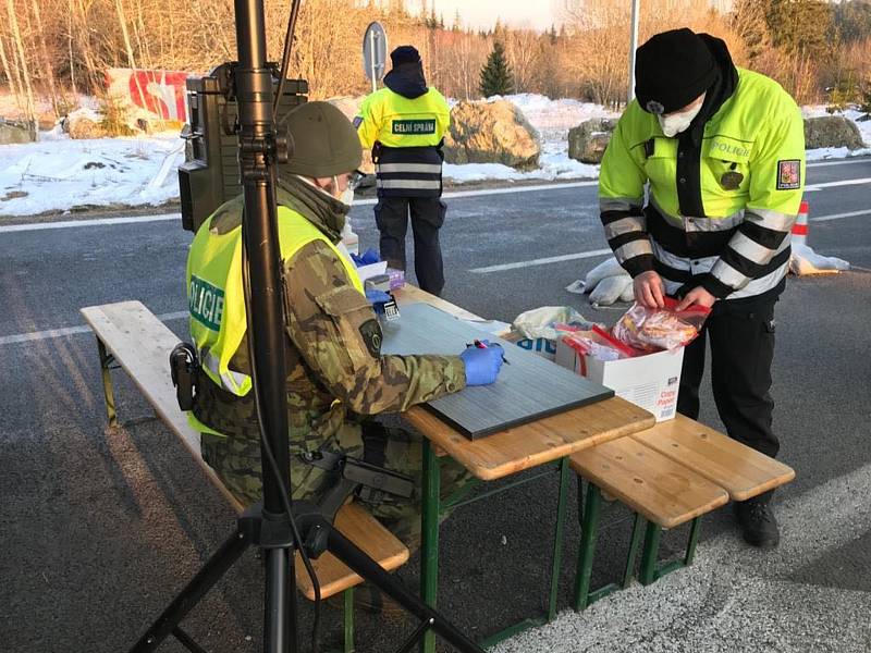 Policisté předávají roušky na hraničních přechodech.