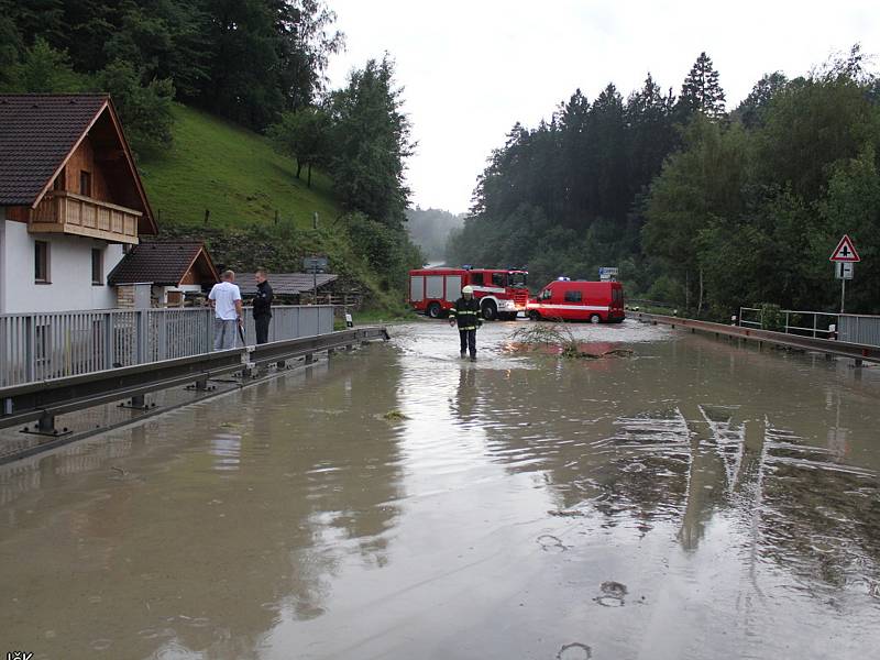 Voda s bahnem valící se v sobotu odpoledne dolů rájovským kopcem tady poškodila silnici, most i vedle stojící dům.